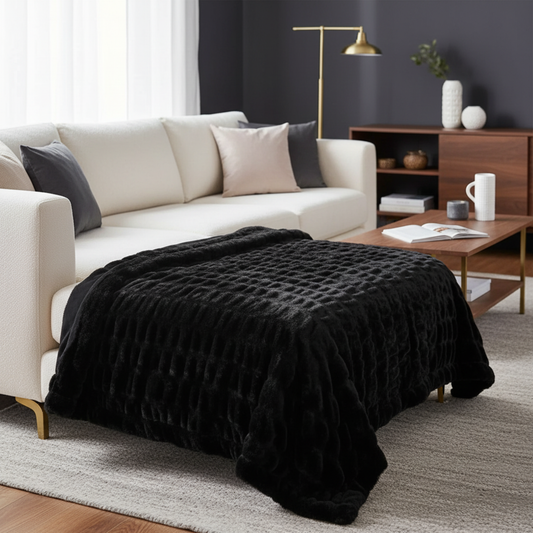 Black ruched faux fur throw draped over a plush white sofa in a luxury spa-inspired room with soft blue accents and gold decor.