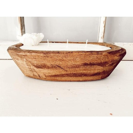 oval shaped wooden bowl filled with white wax with 3 wicks