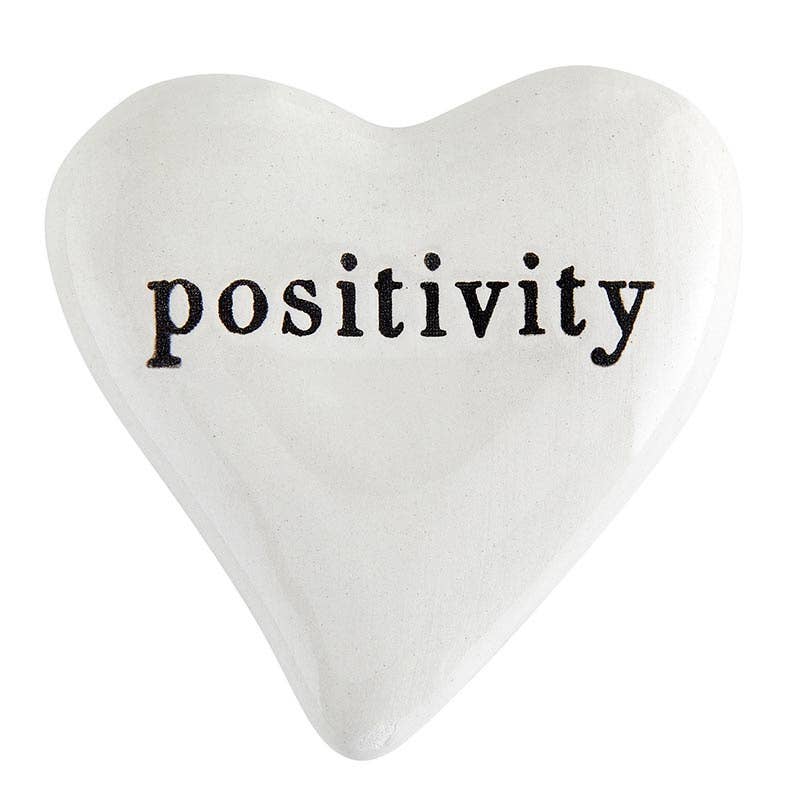 Heart-shaped pillow with the word 'positivity' on a white background